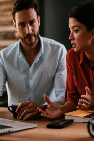 A man and a woman sitting at a desk looking at their computer, potentially researching digital marketing optimization strategies online