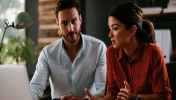 A man and a woman sitting at a desk looking at their computer, potentially researching digital marketing optimization strategies online